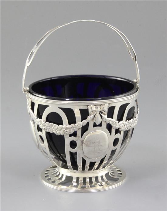 An Edwardian pierced silver sugar basket and blue glass liner, Height to handle 6”/155mm Dia 104mm Weight Silver only: 5.1oz/145grms